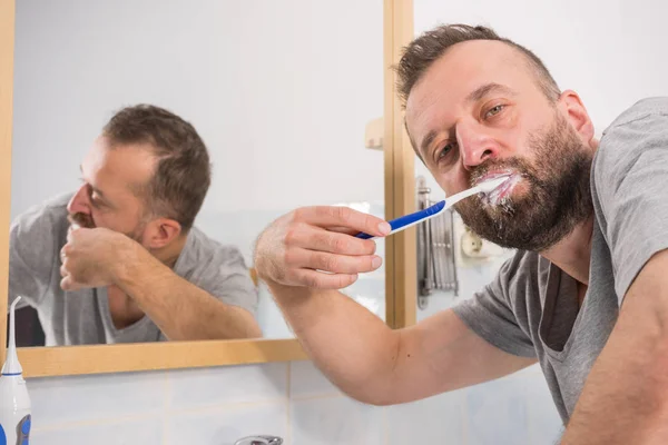 Hombre cepillándose los dientes en el baño — Foto de Stock