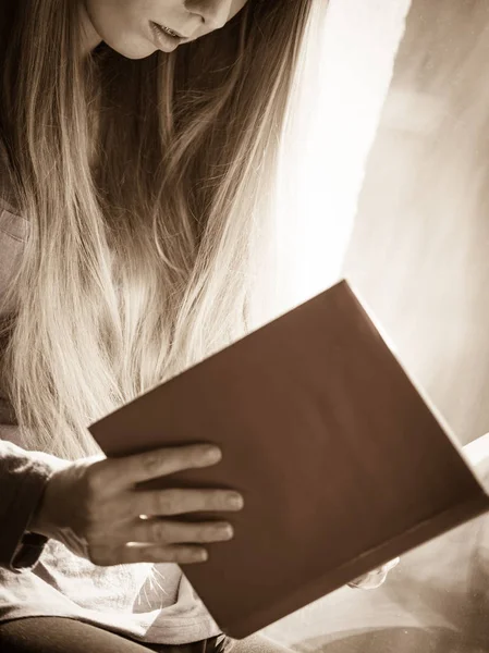 Mulher sentada no peitoril da janela leitura livro em casa — Fotografia de Stock