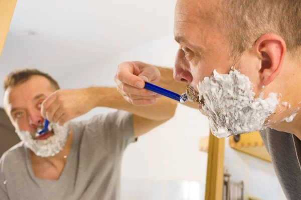 Mann rasiert sich seinen Bart im Badezimmer — Stockfoto