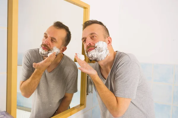 Guy shaving his beard in bathroom — Stock Photo, Image