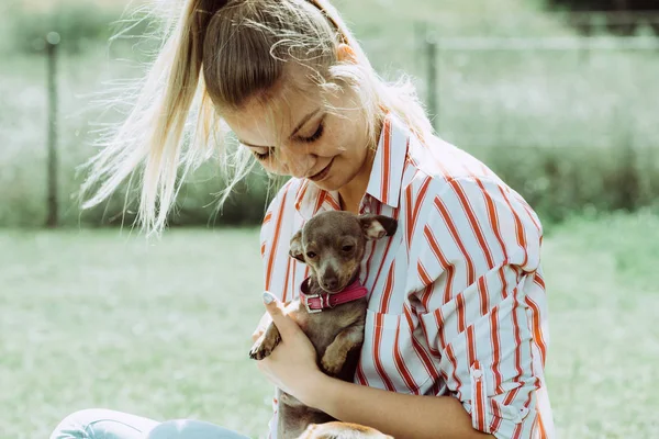 Kvinna leker med lilla hunden utanför — Stockfoto