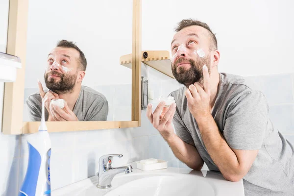 Hombre aplicando crema hidratante en el baño —  Fotos de Stock