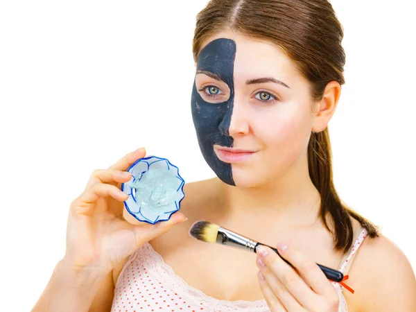 Mädchen schwarze Maske auf halbem Gesicht weißen Schlamm auftragen — Stockfoto