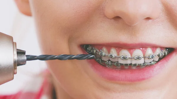 Mulher com aparelho usando broca em seus dentes — Fotografia de Stock