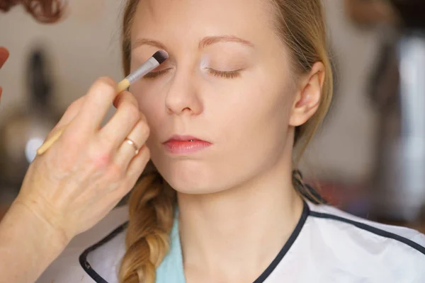 Vrouw krijgt make-up gedaan door kunstenaar — Stockfoto