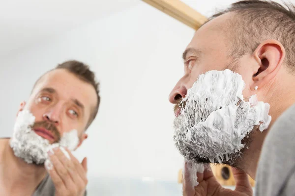 Homme appliquant de la crème à raser sur la barbe — Photo