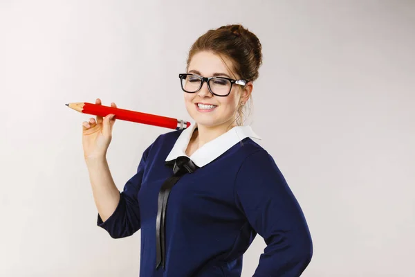 Mujer sonriente sostiene un lápiz grande en la mano — Foto de Stock