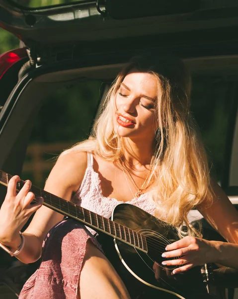 Meisje met gitaar op hatchback auto — Stockfoto