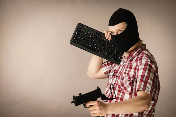 Mann mit Sturmhaube mit Tastatur und Waffe — Stockfoto