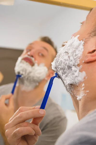 Guy shaving his beard in bathroom — Stock Photo, Image