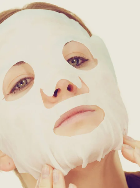 Mujer aplicando máscara de hoja en la cara — Foto de Stock