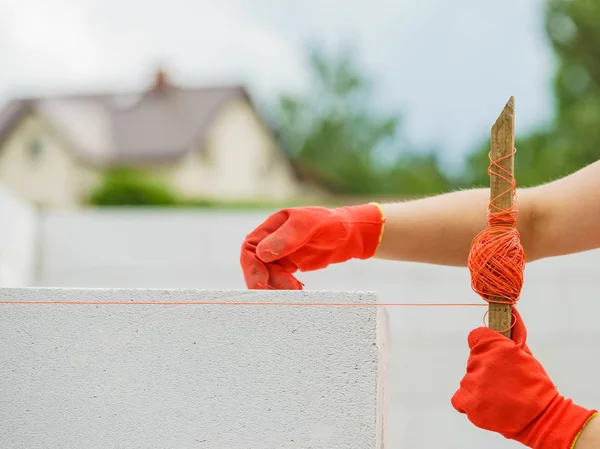 Woman using string as level in wall construction. — Stock Photo, Image