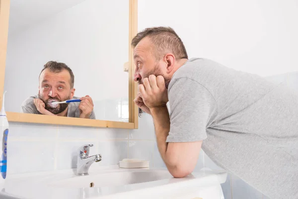 Скучный парень чистит зубы в ванной — стоковое фото