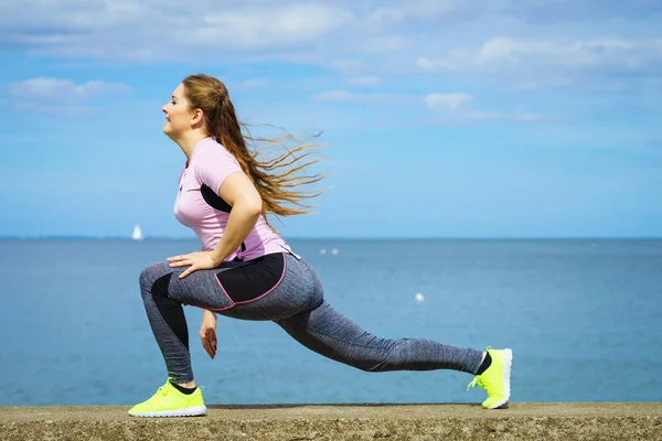 Vrouw uitrekken benen naast zee — Stockfoto