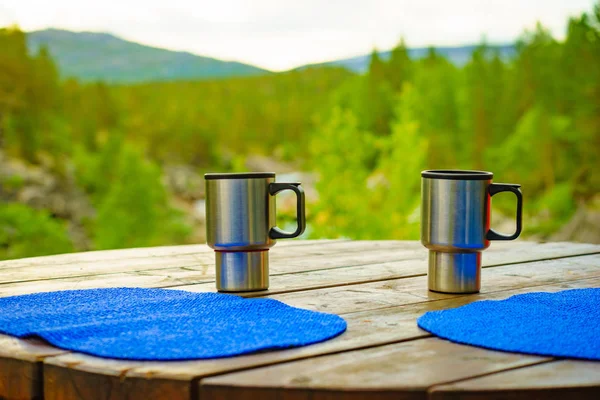 サーマルマグカップ 背景にノルウェーの山の自然とピクニックサイトテーブル サーモスでキャンプ — ストック写真