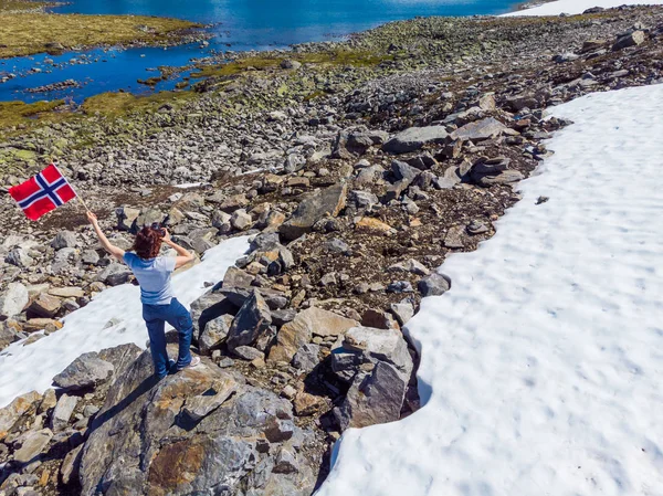 Турист держит в горах норвежский флаг — стоковое фото