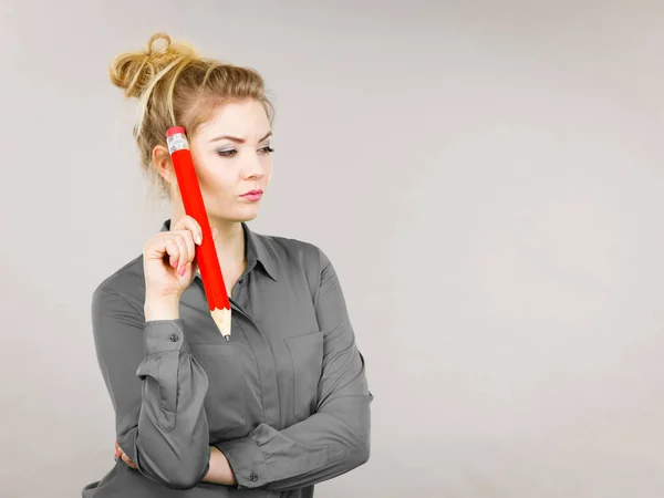 Vrouw verward denken, grote potlood in de hand — Stockfoto