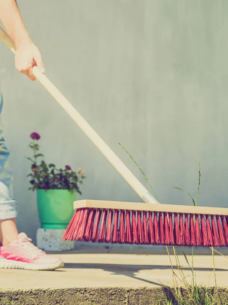 Mujer usando escoba para limpiar patio trasero — Foto de Stock