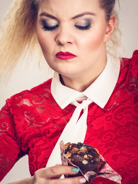 Escéptica mujer sosteniendo cupcake de chocolate —  Fotos de Stock