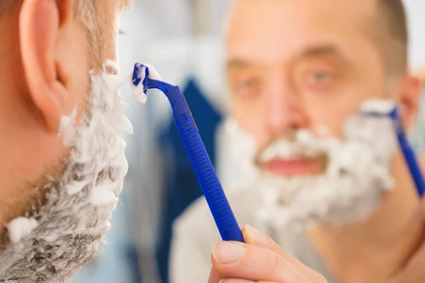 Guy shaving his beard in bathroom — Stock Photo, Image