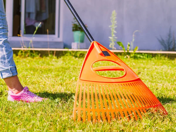 Žena pomocí hrábě vyčistit zahradní trávník — Stock fotografie