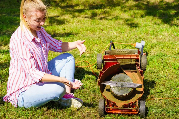 Kvinnlig trädgårdsmästare med trasig gräsklippare — Stockfoto