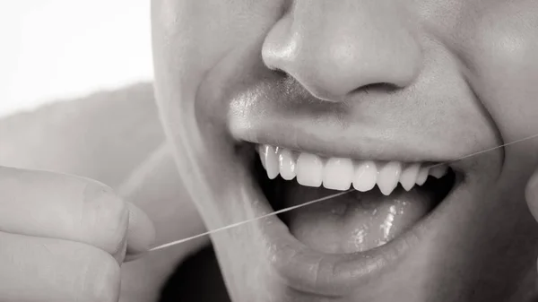 Ung man rengöra hennes vita tänder med tandtråd — Stockfoto
