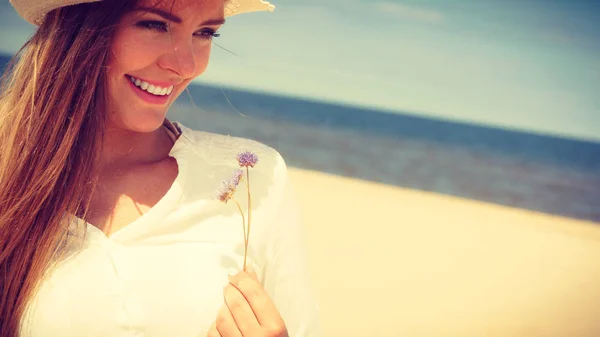 Улыбающаяся девушка с цветами на пляже — стоковое фото