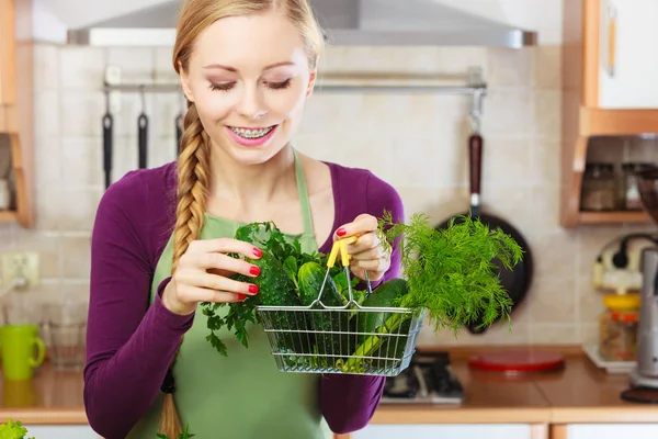 Mujer en cocina teniendo verduras sosteniendo cesta de la compra — Foto de Stock