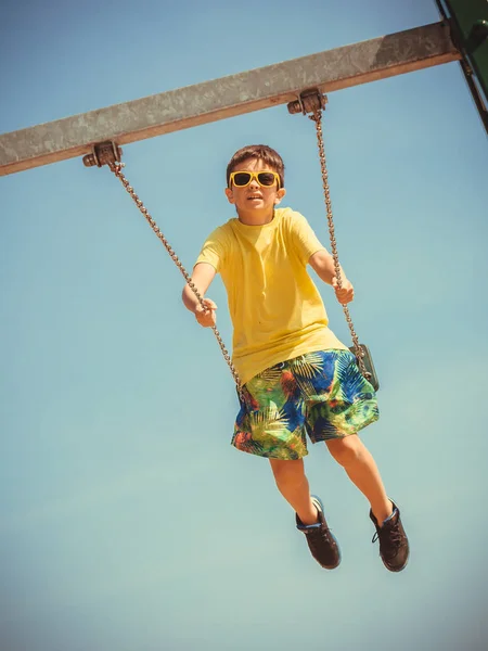 Boy playing swinging by swing-set. — Stock Photo, Image