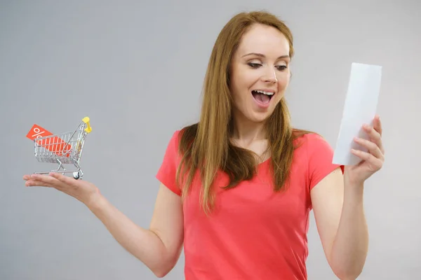 Woman with bill and shopping cart — Stock Photo, Image