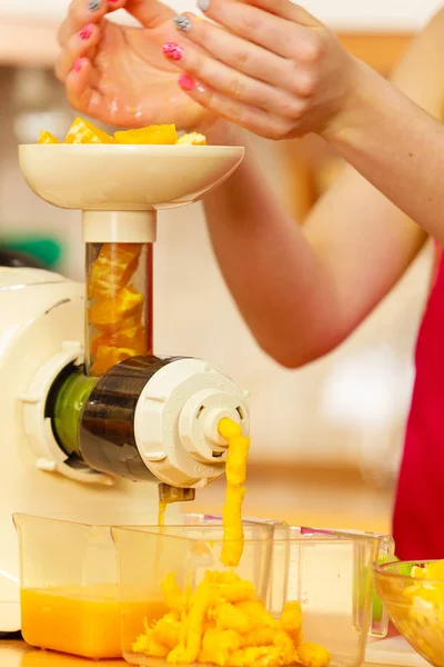 Woman making orange juice in juicer machine — Stock Photo, Image