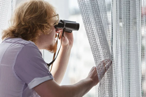 Man with binoculars spying on neighbors — Stock Photo, Image