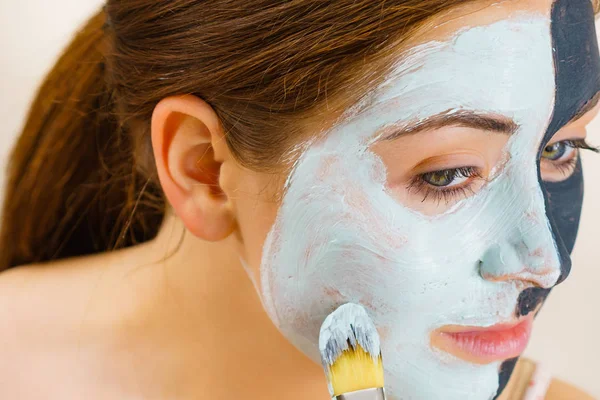 Menina máscara preta na metade do rosto aplicar lama branca — Fotografia de Stock