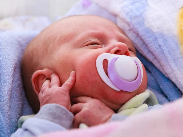 Nahaufnahme eines kleinen Neugeborenen, das mit Zitze im Mund schläft — Stockfoto