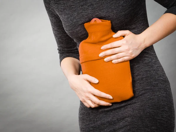 Chica teniendo dolor de estómago, sosteniendo la botella de agua caliente — Foto de Stock