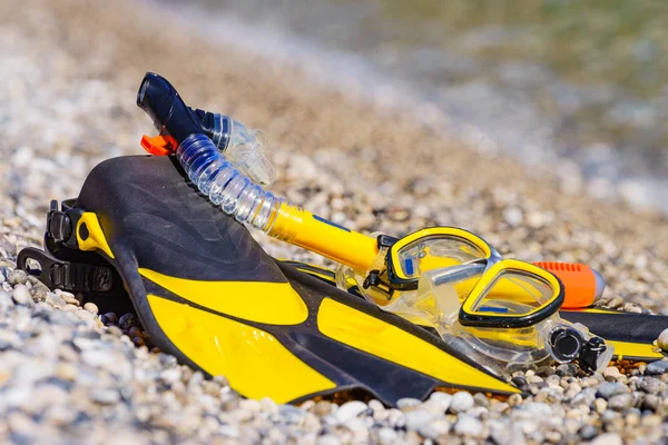 Flippers and snorkeling tube on sea shore — Stock Photo, Image
