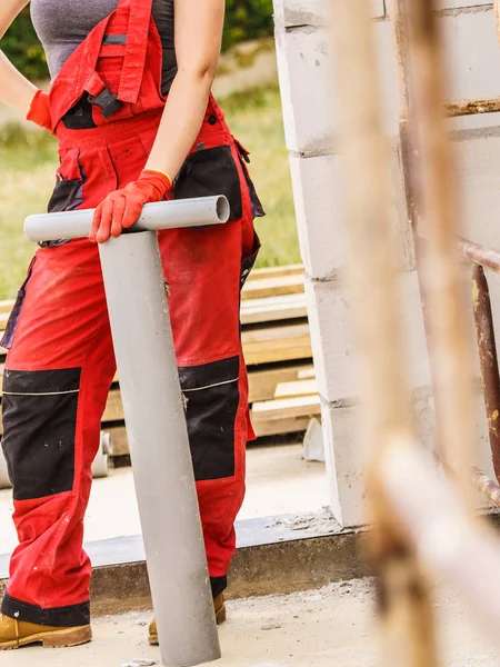 Женщина перевозит трубы на строительной площадке — стоковое фото
