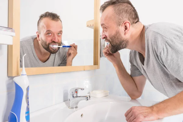 Hombre cepillándose los dientes en el baño — Foto de Stock