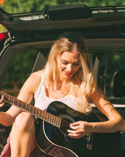 Meisje met gitaar op hatchback auto — Stockfoto