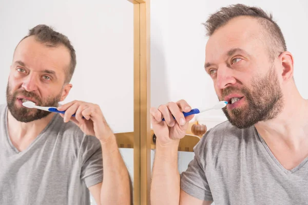 Hombre cepillándose los dientes en el baño —  Fotos de Stock