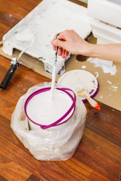 Person mischt weiße Farbe in Eimer. — Stockfoto