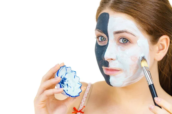 Mädchen schwarze Maske auf halbem Gesicht weißen Schlamm auftragen — Stockfoto