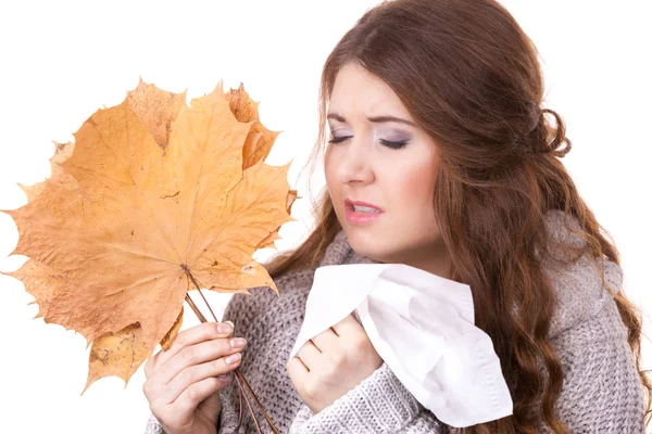 Sick woman sneezing in tissue holds autumn leaf — Stock Photo, Image