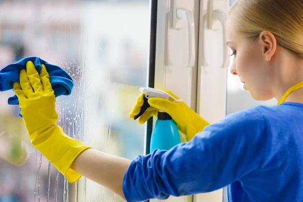 Kobieta sprzątająca okno w domu — Zdjęcie stockowe