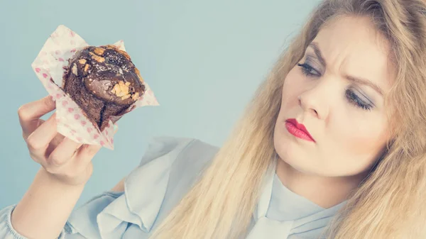 Skeptical woman holding chocolate cupcake muffin — Stock Photo, Image