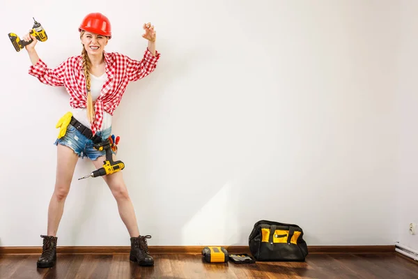 Kvinna som bär hjälm, verktygsbälte om att borra vägg — Stockfoto