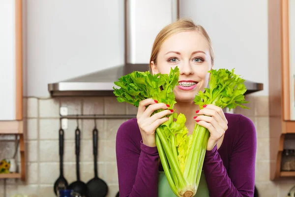 Femme dans la cuisine tient céleri vert — Photo