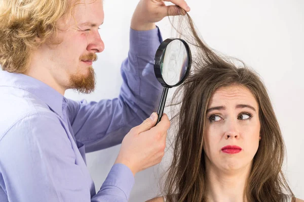 Чоловік дивиться на волосся жінки через збільшувач — стокове фото
