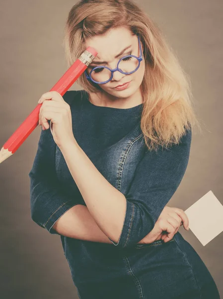 Mujer confusa sostiene papel de lápiz grande en la mano — Foto de Stock